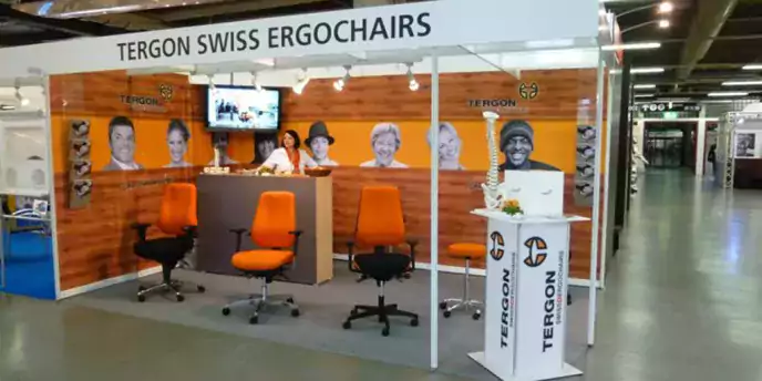 Messestand von Tergon Swiss Ergochairs. Übersichtlich aufgebaut mit überwiegend orangenen Elementen.